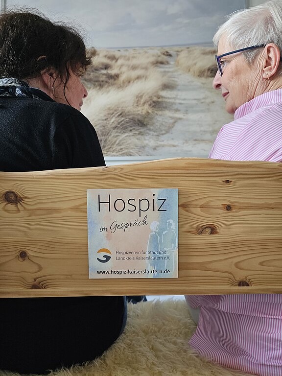 Zwei Menschen auf einer Bank sitzend von hinten