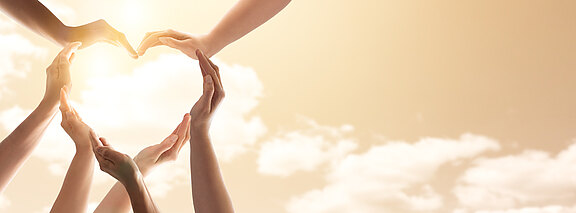 Sieben Hände formen gemeinsam ein Herz